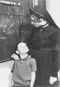 876941 Afbeelding van een jongetje voor het schoolbord in een klaslokaal van de Piusschool voor R.K. onderwijs voor ...